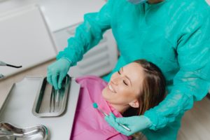 Woman sitting back in a dental chair. The dentist is holding and exam mirror near her face